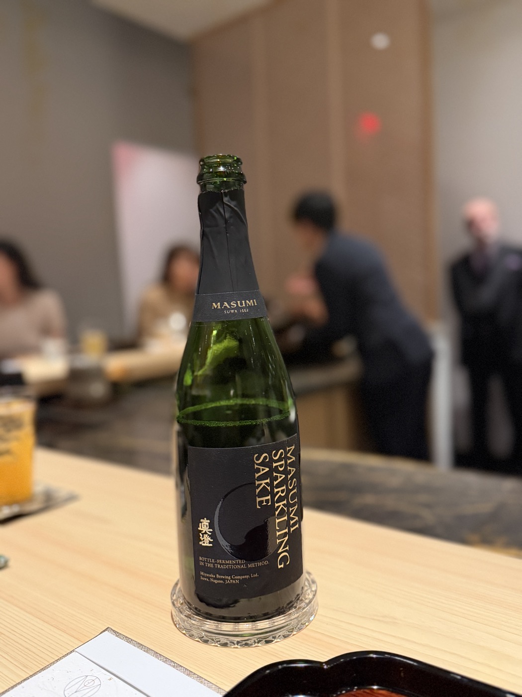A green bottle of Masumi sparkling sake on the counter