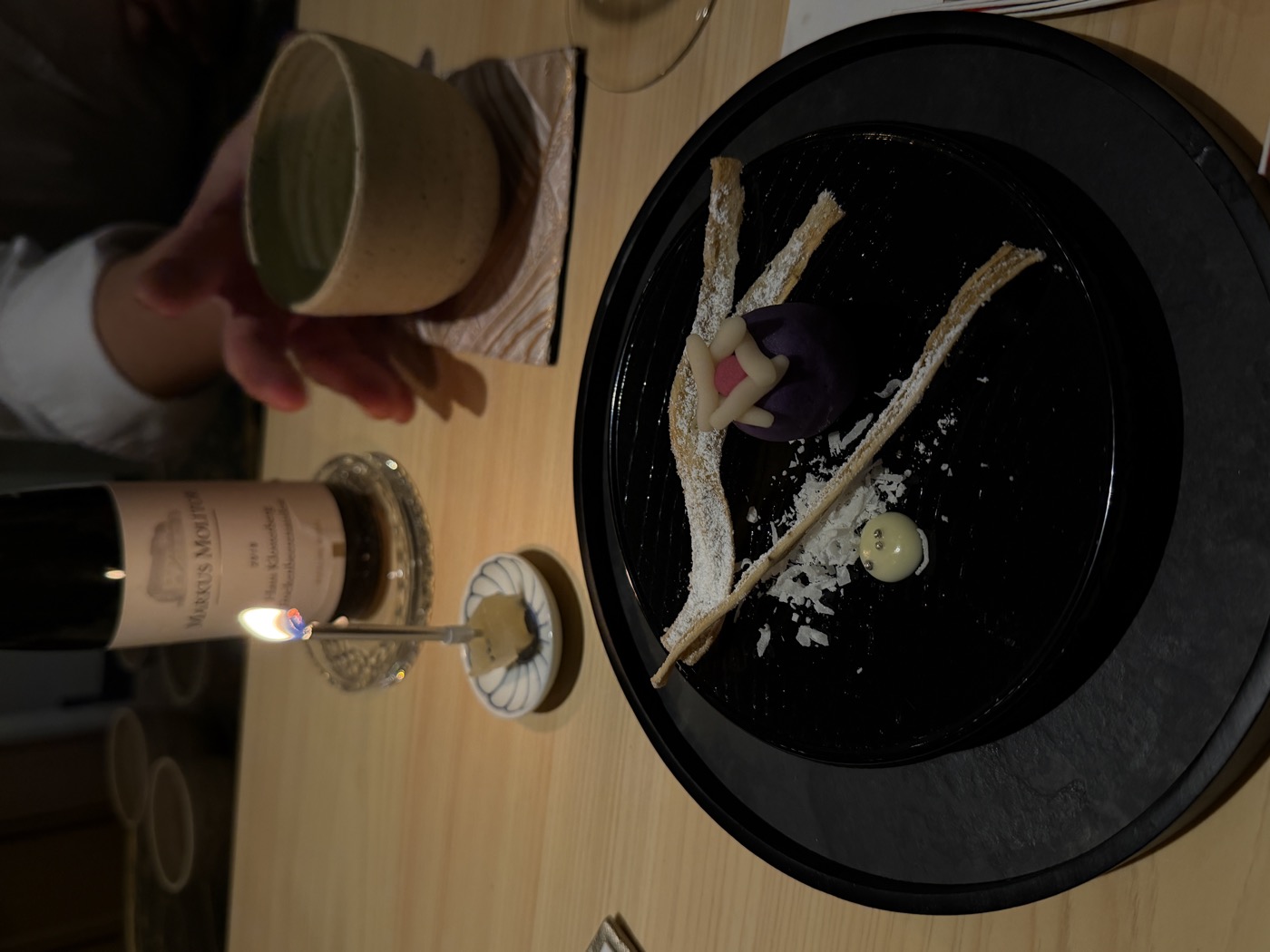 A dark plate by candlelight with a delicate sweet