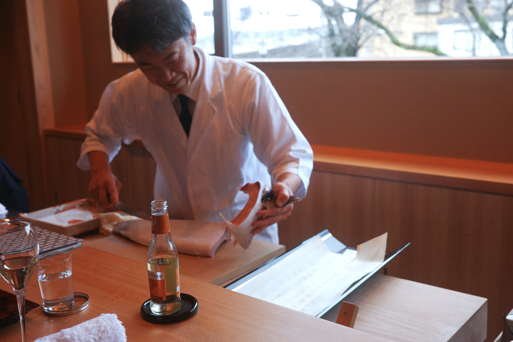 The chef at Ebitei Bekkan, smiling as he breaks down a fish at the counter