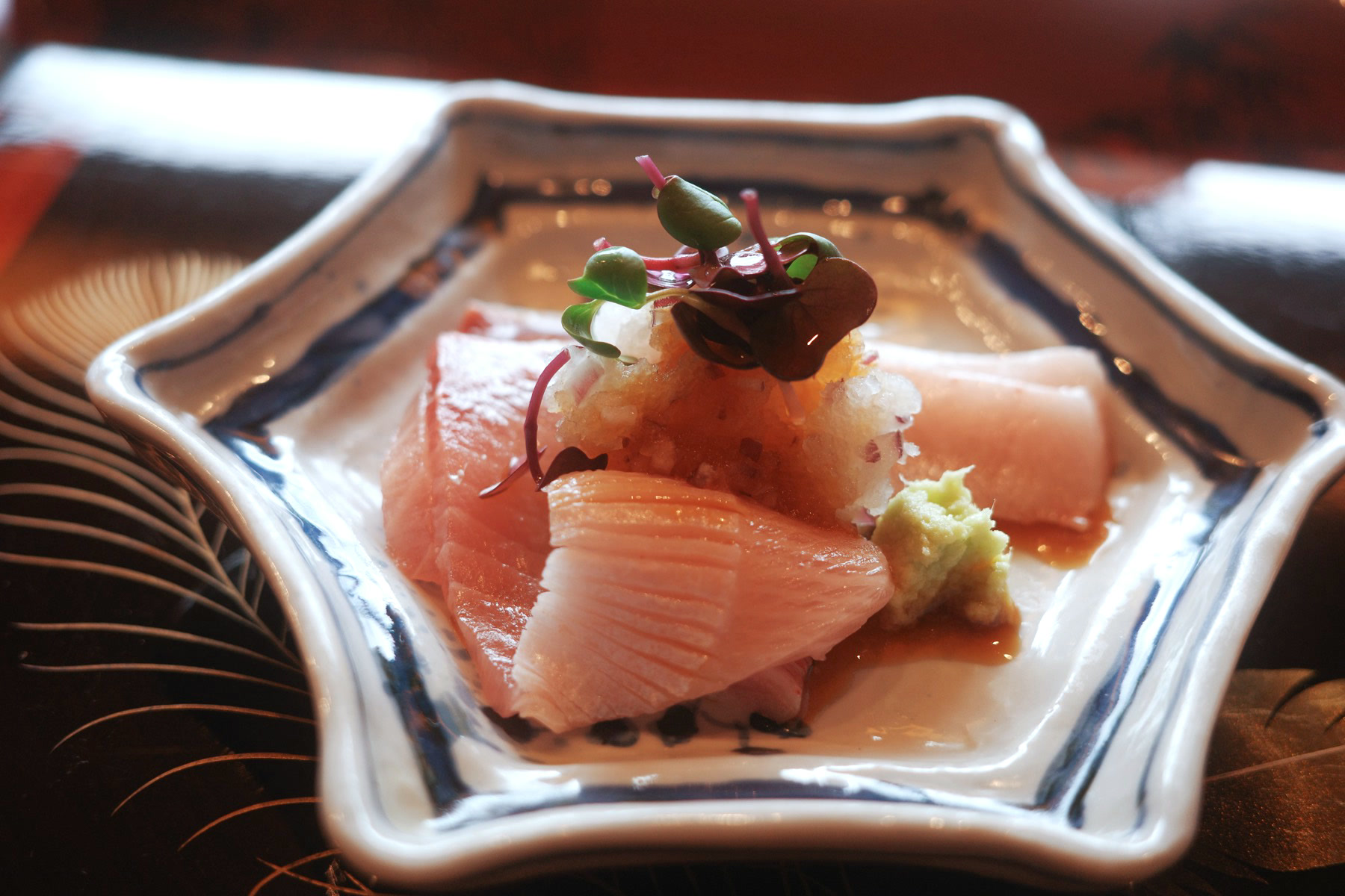 Sashimi on a blue-and-white hexagonal plate with grated daikon, microgreens and wasabi