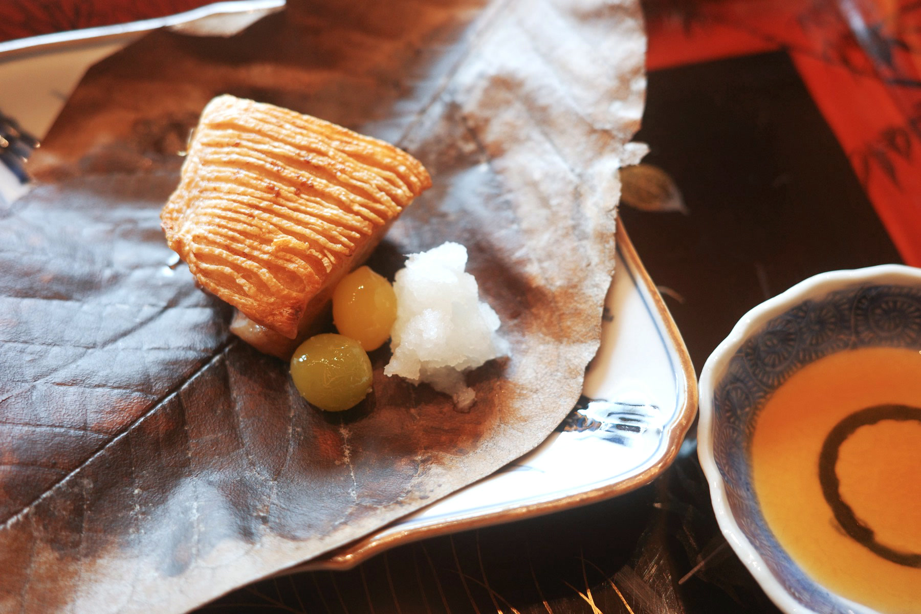 Grilled yellowtail on a dried magnolia leaf with a ginkgo nut and grated daikon