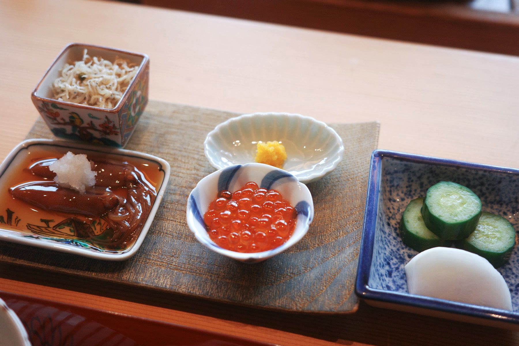 The rice service spread: a cup of baby sardines, marinated squid in a painted dish, salmon roe, yuzu, and nuka pickles