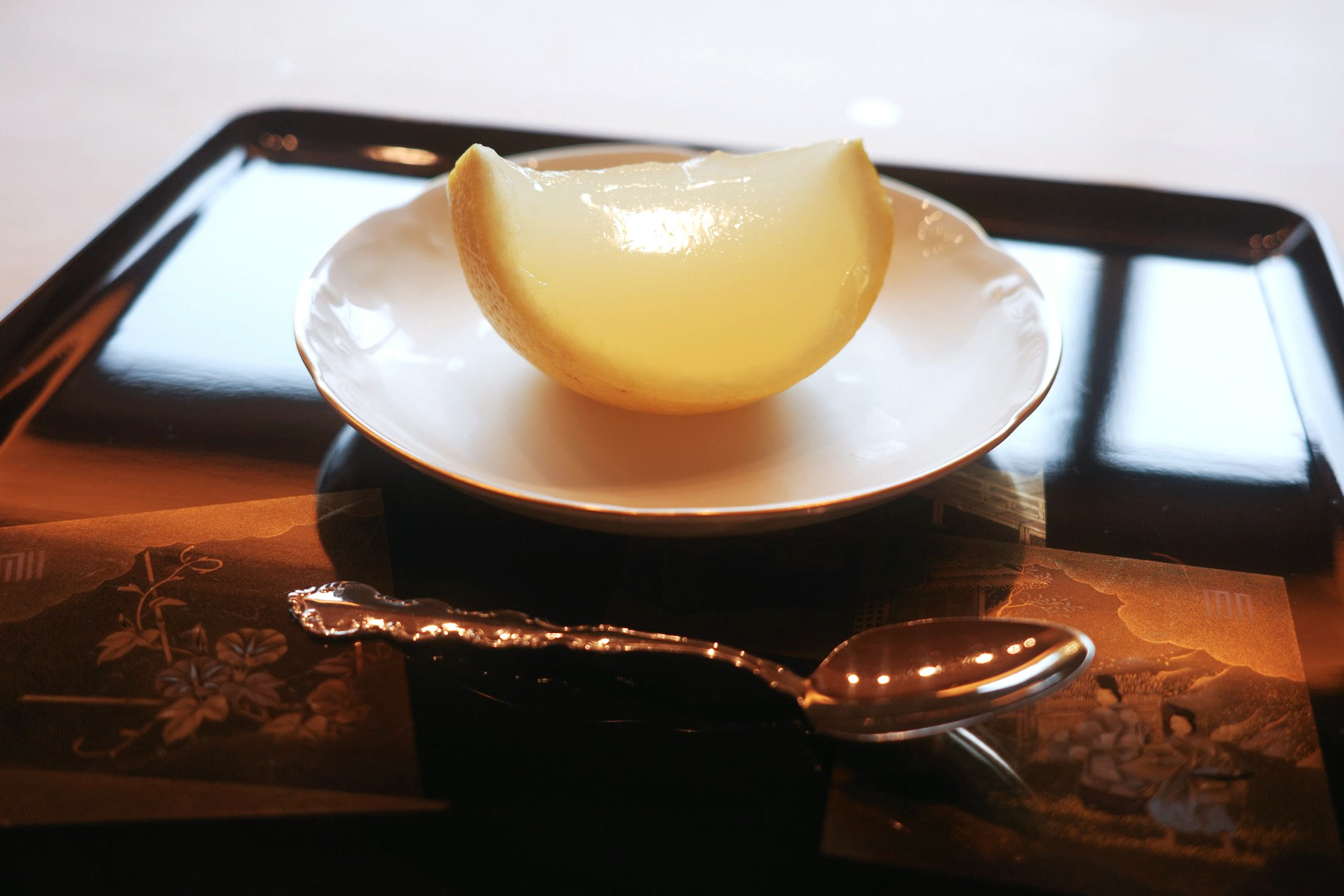 A citrus fruit hollowed out and filled with its own pale jelly, served in the rind on a small plate