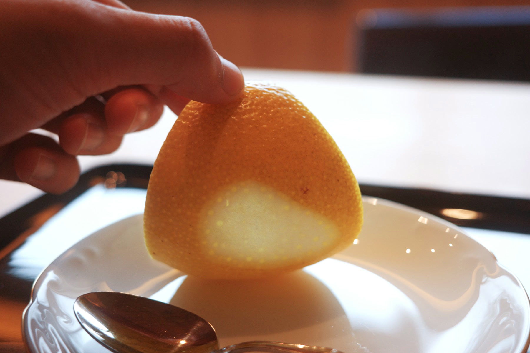 A hand lifting the citrus-jelly rind to show the set jelly inside