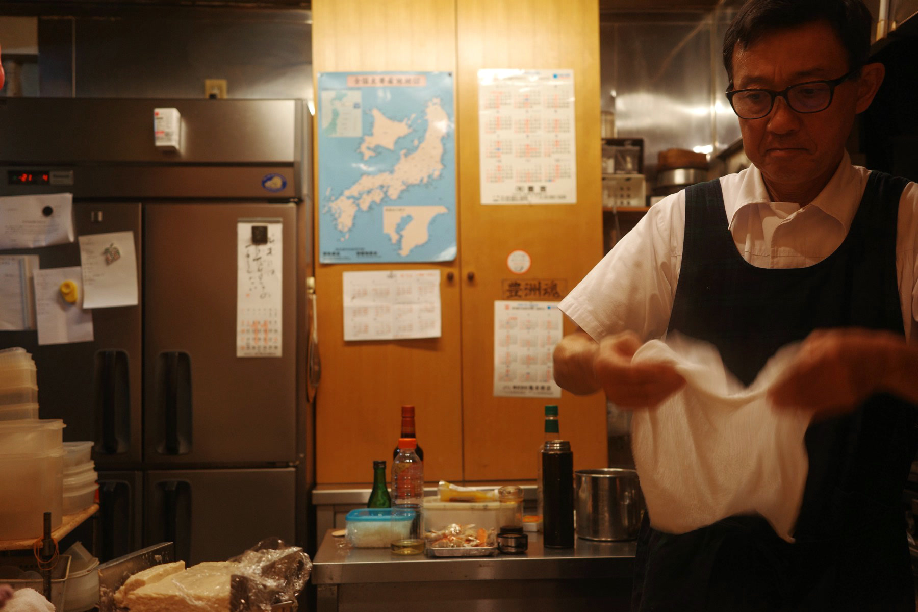 The chef at Satoki working in his small kitchen, a map of Japan on the wall behind him
