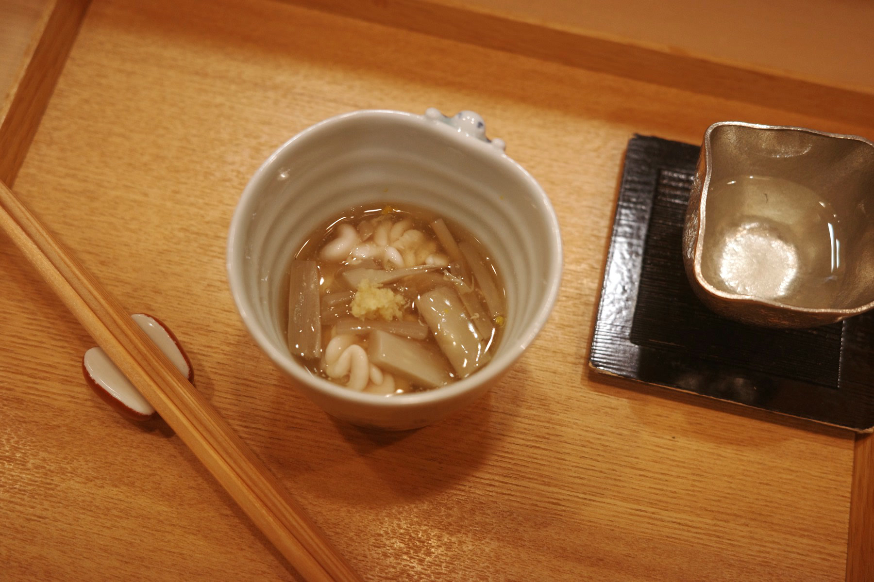 A small cup of clear broth with cod milt, mushrooms and burdock