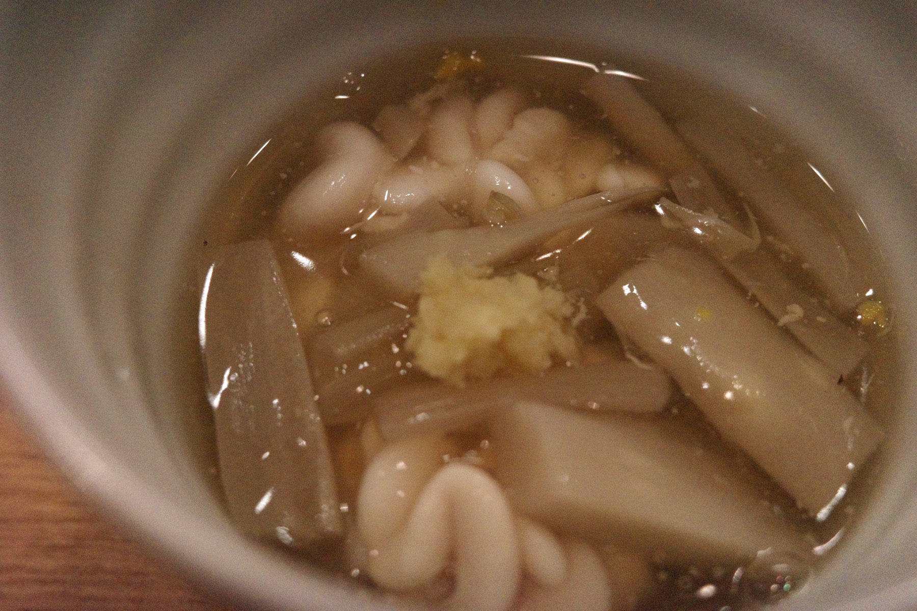 Close-up of the cod milt and mushrooms in broth with grated ginger
