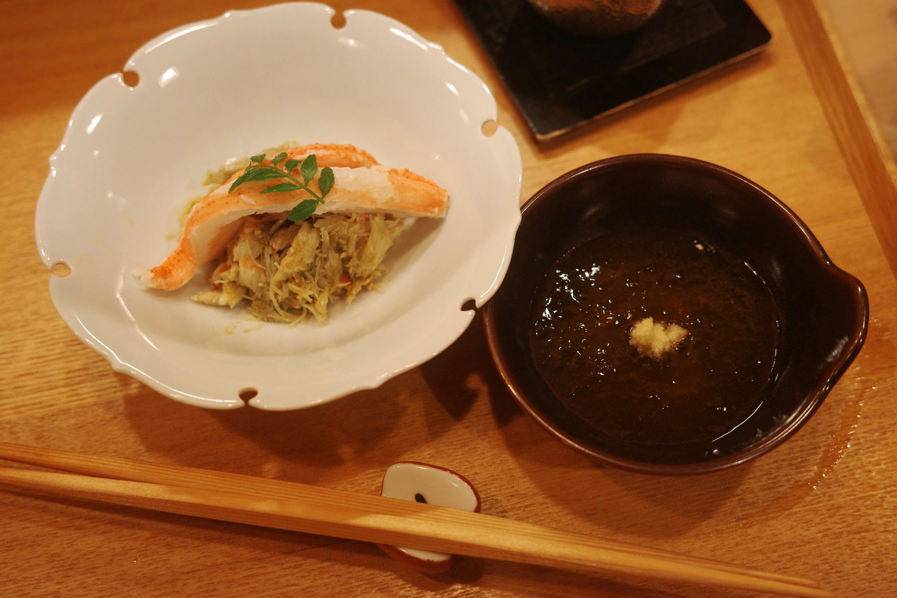 Snow crab leg over picked crab meat, with a small bowl of crab vinegar