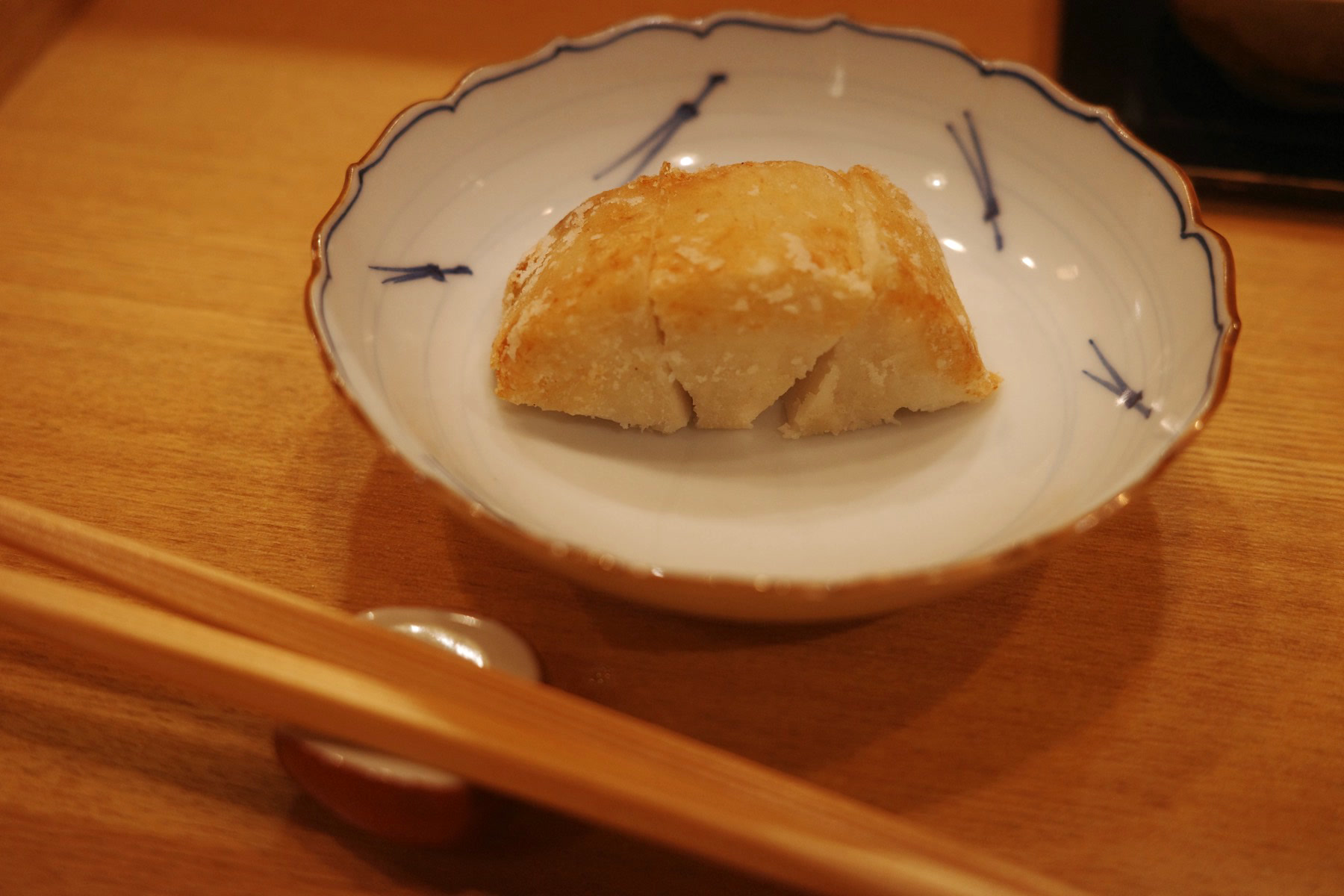 A golden, blistered grilled morsel on a dragonfly-patterned plate
